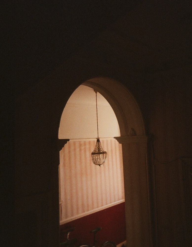 An arched doorway inside the flat, looking through to a lit room with a small chandelier and striped wallpaper.